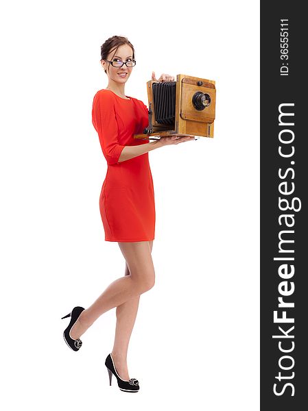 Girl in red dress with an old camera on a white background