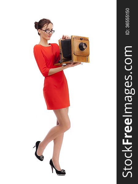 Girl in red dress with an old camera on a white background