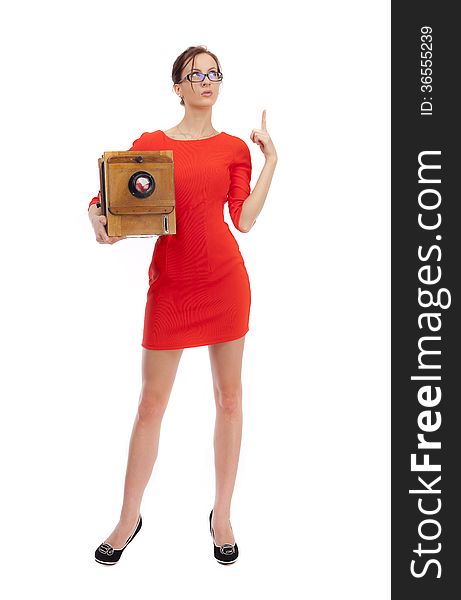 Girl in red dress with an old camera on a white background