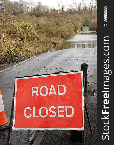 A country road is closed as a swollen river breaks its banks. Hampshire, England UK. A country road is closed as a swollen river breaks its banks. Hampshire, England UK