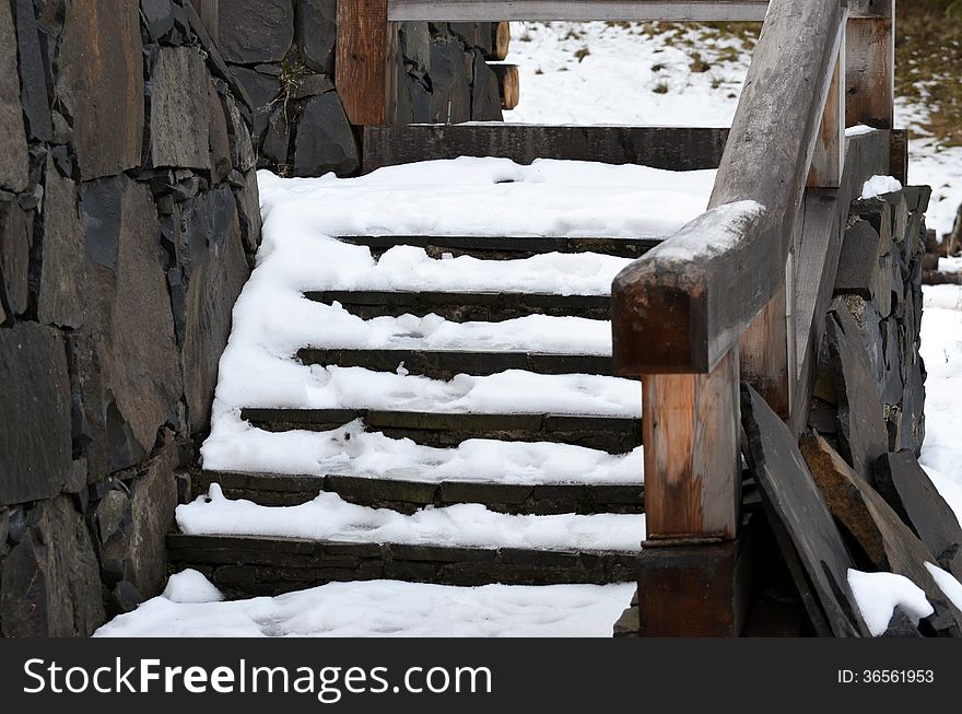 Wooden stairs covered by snow .