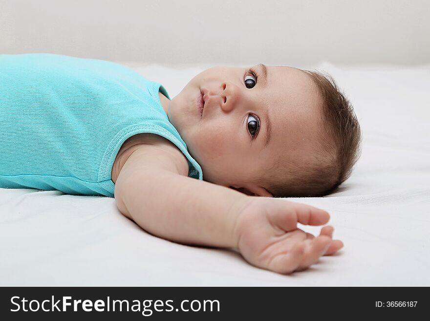 Baby boy laying on bed, white background