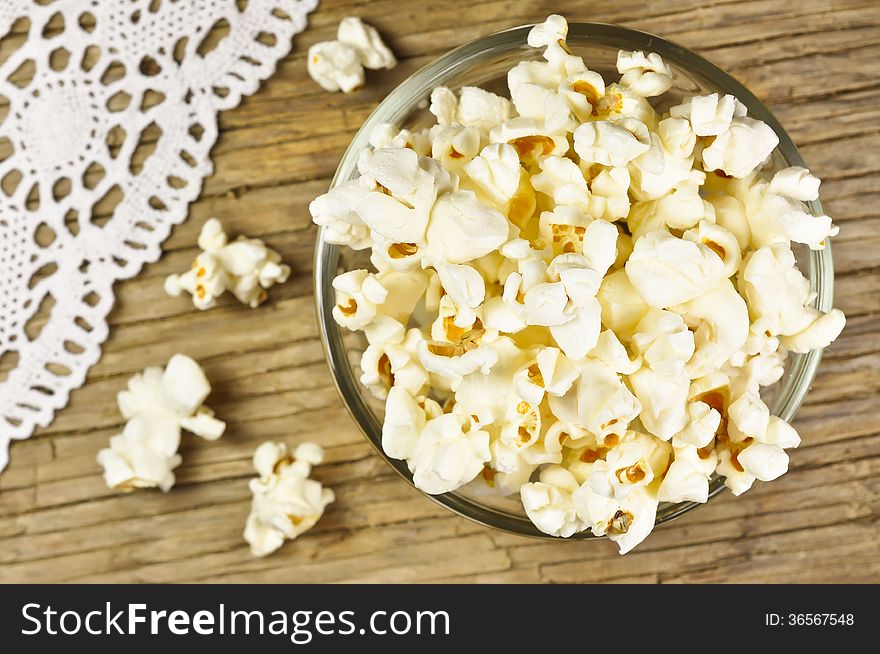 Popcorn in bowl on wooden table with white lace