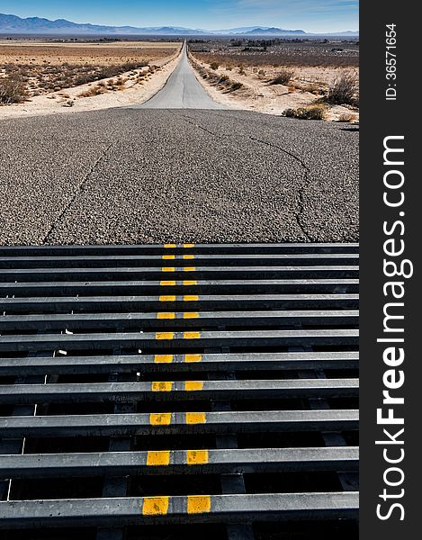 Double yellow lines on a cattle grate crossing in a road to mountains