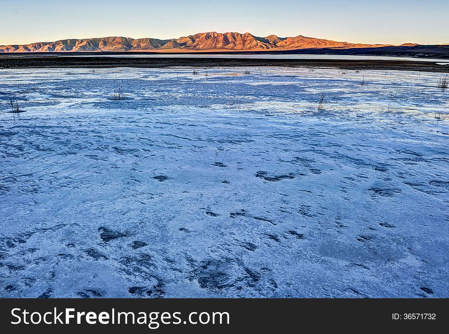 Ice and snow over a lake with sunny mountains in the background. Ice and snow over a lake with sunny mountains in the background