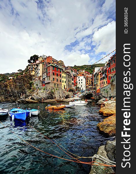 Cliff, boats and colored houses of Riomaggiore in Italy