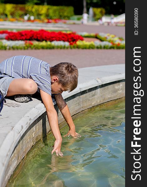 Little boy putting his hands into the water in the pond, summer day. Little boy putting his hands into the water in the pond, summer day