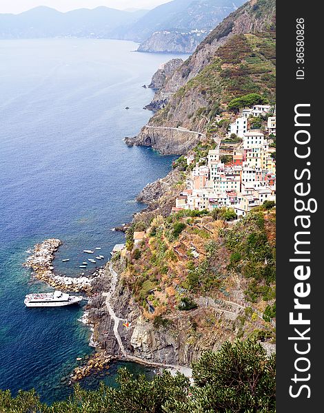 Cliff, boats and colored houses of Riomaggiore in Italy