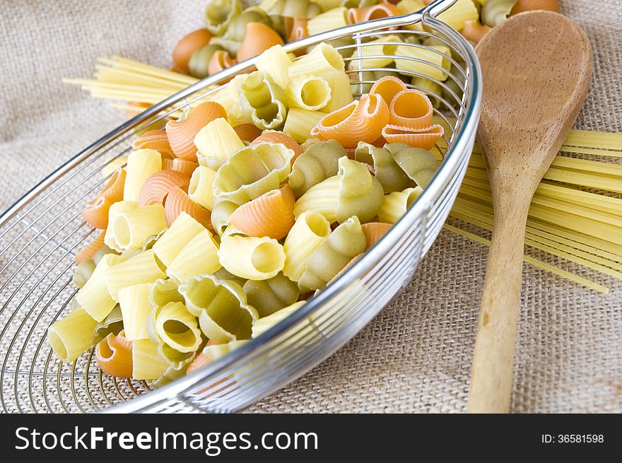 Colorful uncooked pasta with kitchenware