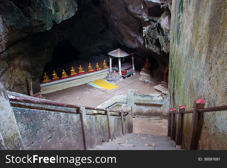 The entrance of the ancient cave with golden Buddha in Thailand