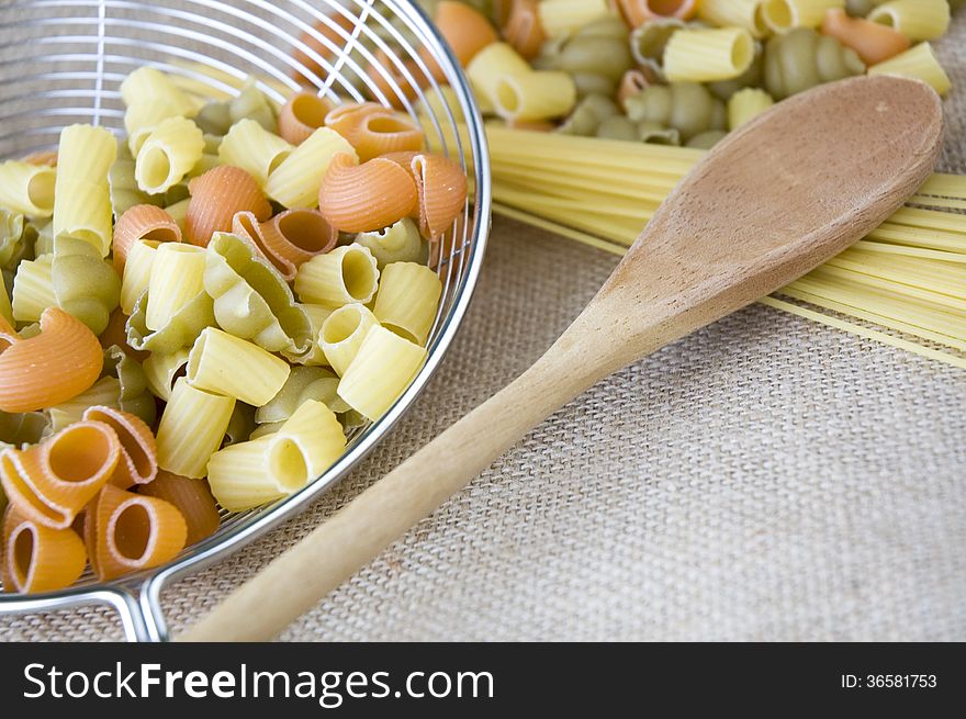 Close up wooden spoon put on uncooked pasta. Close up wooden spoon put on uncooked pasta