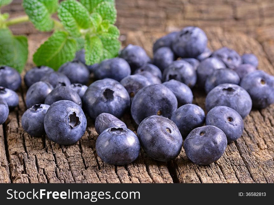 Fresh blueberries with mint leaves on a wooden background