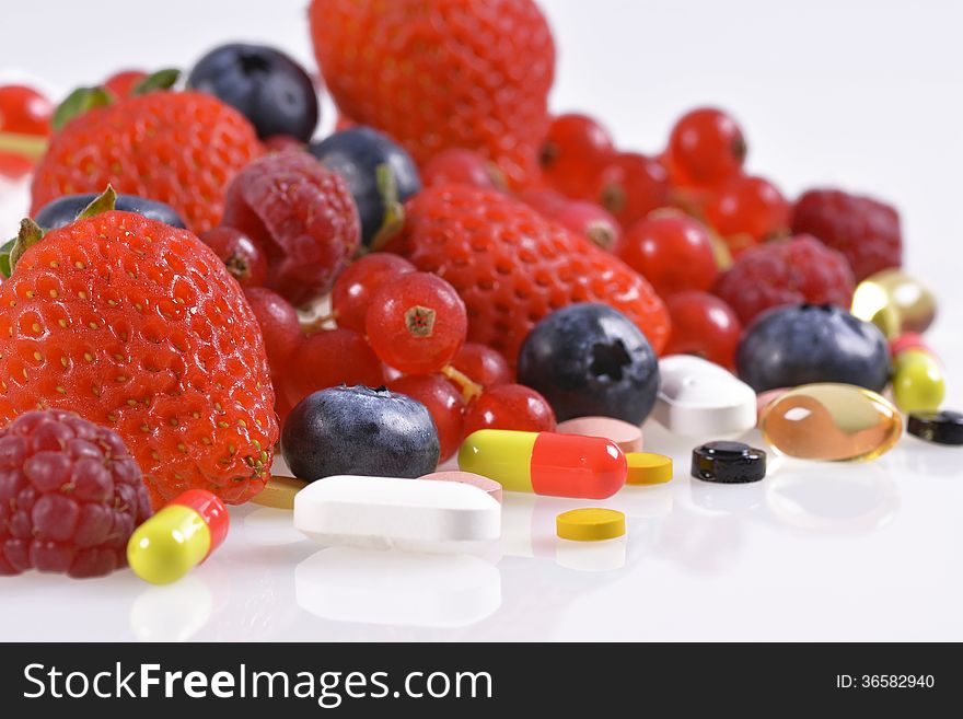 Berries, vitamins and nutritional supplements on white background