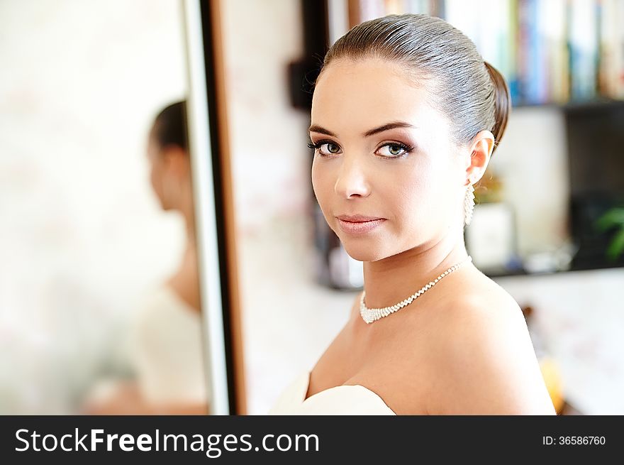 Happy bride near mirror in wedding day