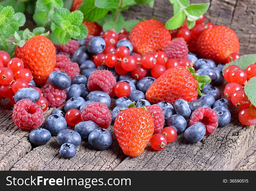 Fresh berries with mint leaves on a wooden background. Fresh berries with mint leaves on a wooden background