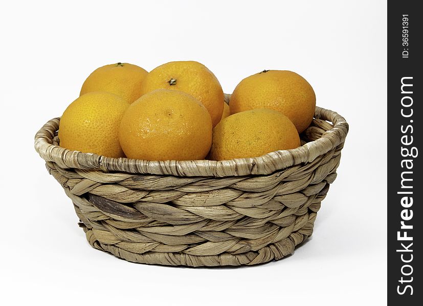 Clementine oranges in a brown wicker basket against a white background. Clementine oranges in a brown wicker basket against a white background