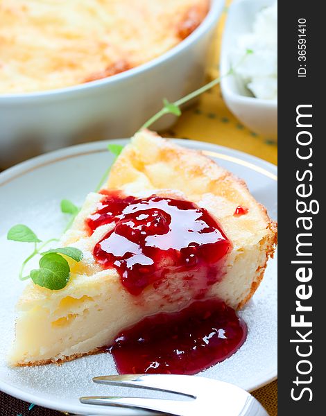 Piece of cheesecake with raspberry jam on the table