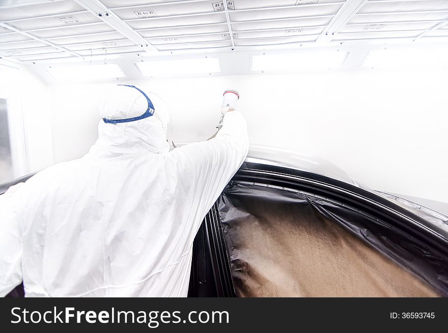 Automotive industry - engineer painting and working on a black body of a car