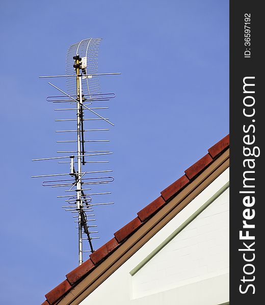 Tv antenna on red roof of house in sunny day. Tv antenna on red roof of house in sunny day