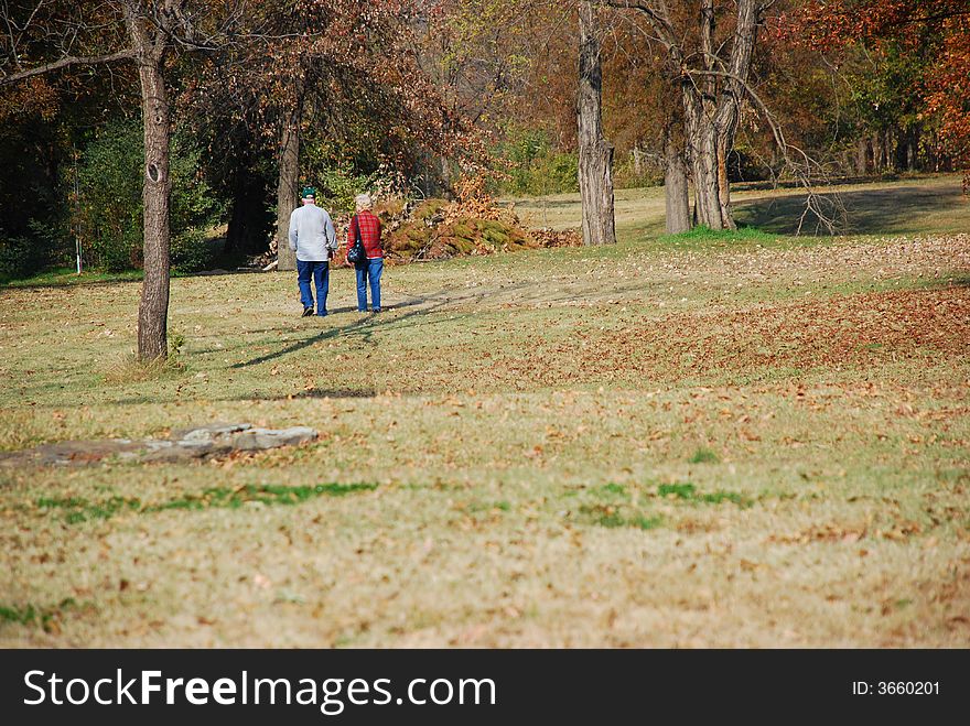 Older couple walks in park on autumn day. Older couple walks in park on autumn day