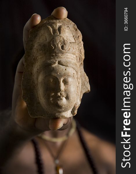 Close up of a man hand holding a stone buddha statue over black background. Close up of a man hand holding a stone buddha statue over black background