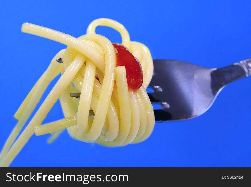 Pasta on fork on blue background