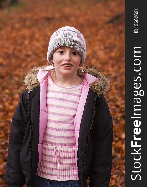 Girl in park surrounded by autumn leaves