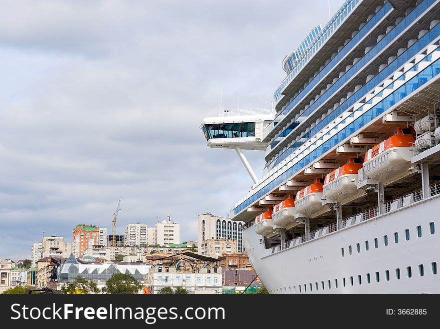 Russia. Round the world cruise ship is landing at pier in port Vladivostok. On a background there are houses of Vladivostok city. Russia. Round the world cruise ship is landing at pier in port Vladivostok. On a background there are houses of Vladivostok city.