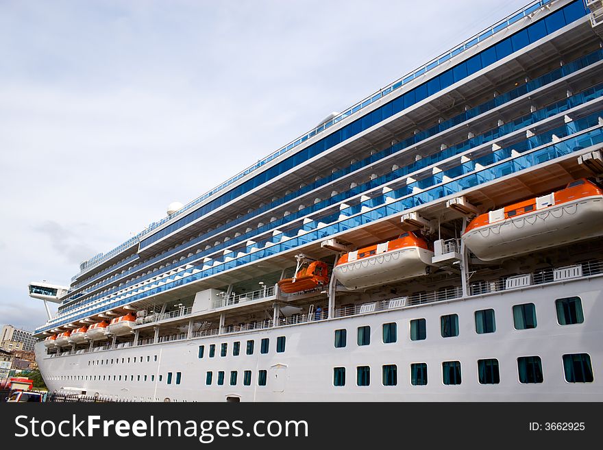 Russia. Round the world cruise ship is landing at pier in port Vladivostok. On a background there are houses of Vladivostok city. Russia. Round the world cruise ship is landing at pier in port Vladivostok. On a background there are houses of Vladivostok city.