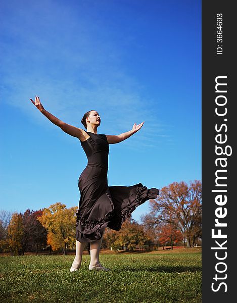 Ballerina performing outdoors with blue sky