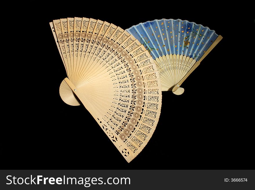 Two hand-held fans on black background