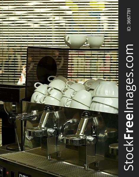 Clean coffee cups and a coffee machine in a closed cafe