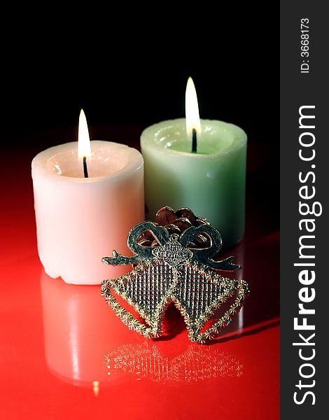 Burning couple candle and christmas ring bell on the the dark red color background
