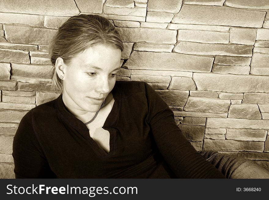 Girl sitting against a brick wall. Girl sitting against a brick wall