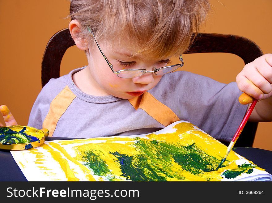 Little boy painting at easel