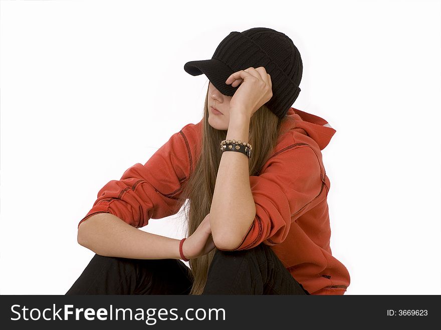 The girl-teenager in a red jacket and a black cap sits. The girl-teenager in a red jacket and a black cap sits