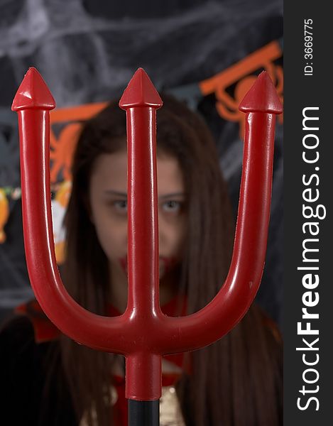 A trident with a girl in a halloween costume in the background. A trident with a girl in a halloween costume in the background