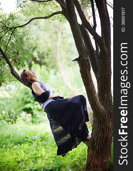 Young girl laughing, resting on a tree branch. Young girl laughing, resting on a tree branch