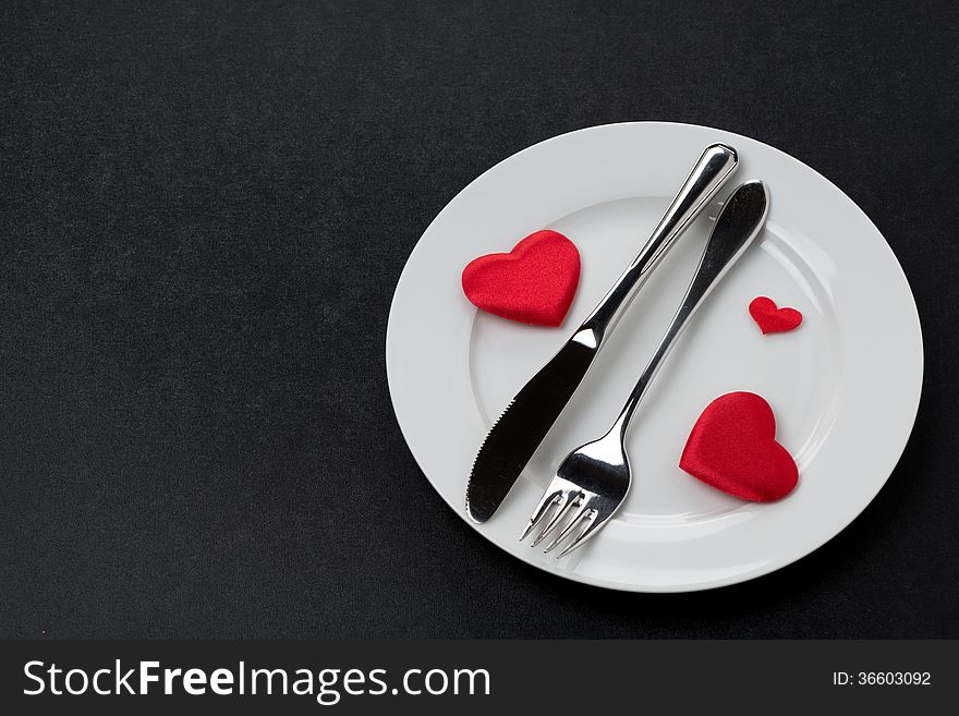 Fork, knife and a red heart on a plate, horizontal