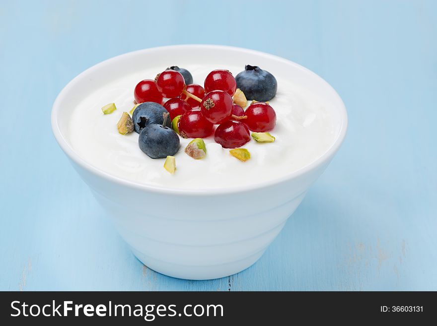Fresh sweet yogurt with berries and pistachios in a bowl, close-up, horizontal. Fresh sweet yogurt with berries and pistachios in a bowl, close-up, horizontal