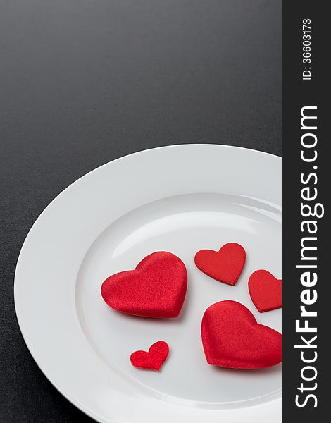 Red hearts on a white plate, close-up, vertical