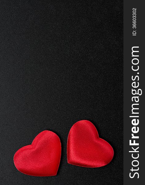 Two red hearts on a black background, top view