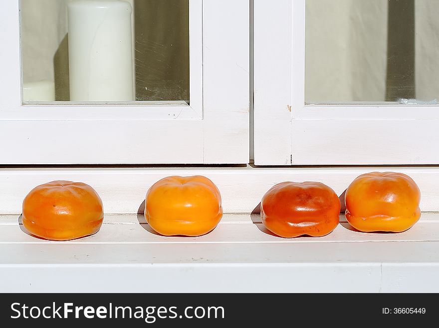 Red persimmons on white windowsill