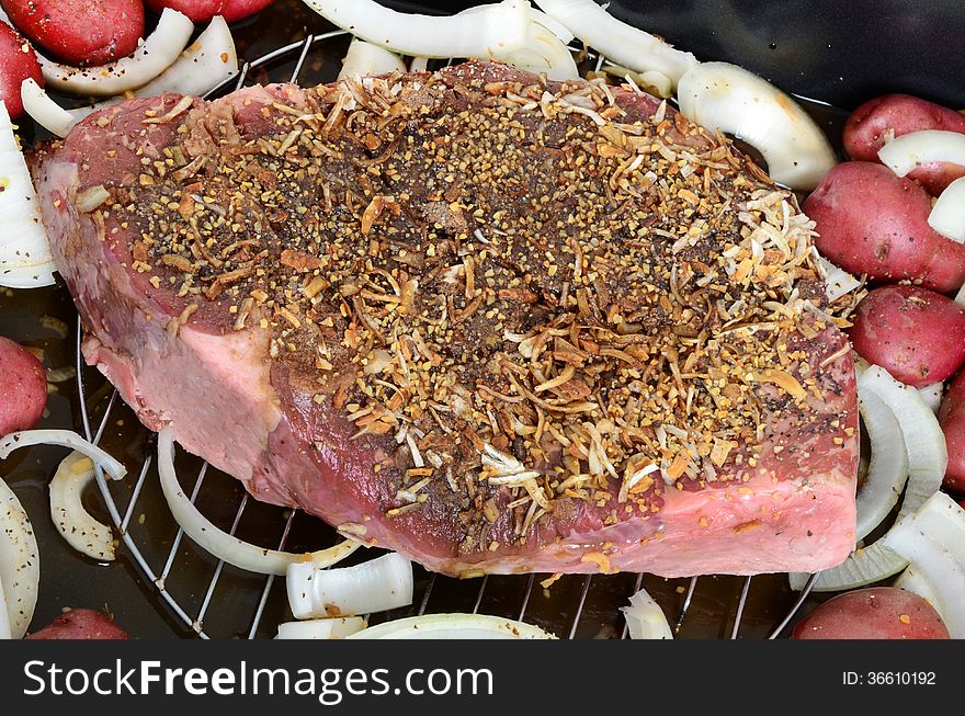 Raw meat seasoned roast with onions and potatoes