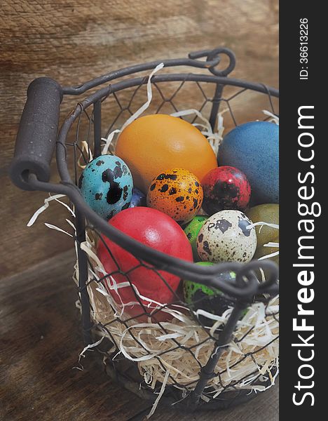 Colorful easter eggs in a basket on wooden background