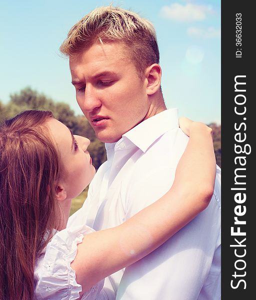 Portrait of Beautiful Young Couple in Love on nature. Man and Woman Smiling Charmingly. Young Couple Kissing Summer on Sunny Sky Background. Portrait of Beautiful Young Couple in Love on nature. Man and Woman Smiling Charmingly. Young Couple Kissing Summer on Sunny Sky Background