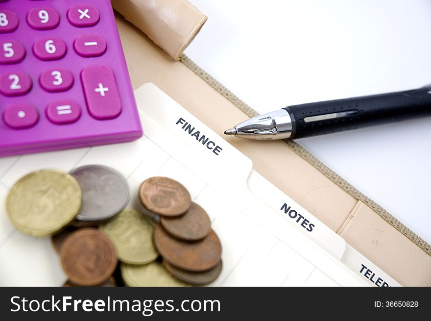 Pen point to finance page with coins and pink calculator. Pen point to finance page with coins and pink calculator