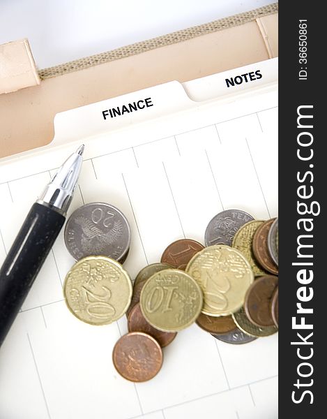 Euro coins with pen on finance page