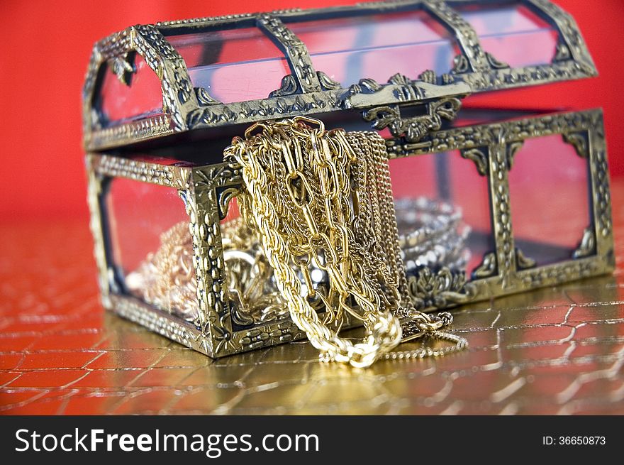 Golden jewelry in treasure chest with red background. Golden jewelry in treasure chest with red background