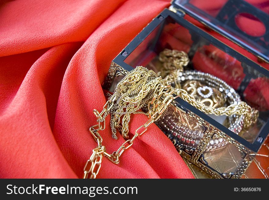 Golden jewelry in treasure chest put on red background. Golden jewelry in treasure chest put on red background